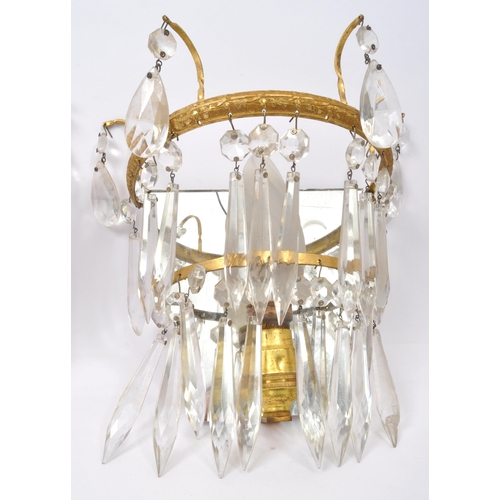 961 - A pair of early 20th Century gilt metal wall lights. Having loose mirror back with decorated gilt me... 