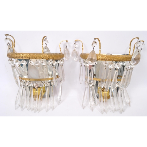 961 - A pair of early 20th Century gilt metal wall lights. Having loose mirror back with decorated gilt me... 