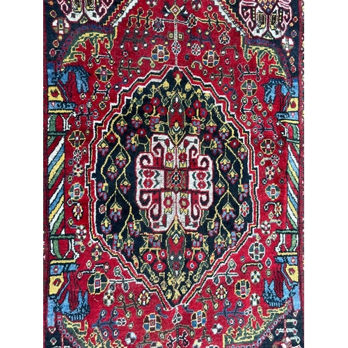 931 - An early 20th Century Gashai Persian Islamic carpet floor rug. Having virgin pile wool with red and ... 