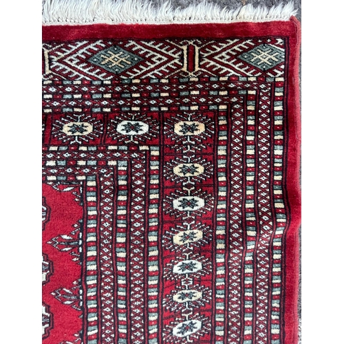 950 - A vintage 20th Century Bucahra Persian Islamic carpet floor rug. Having repeating central medallions... 