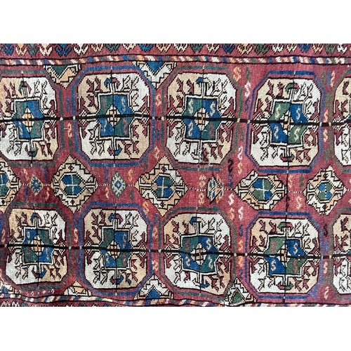 975 - A vintage early 20th Century Afghan Bukara Persian Islamic carpet floor rug. Having repeating medall... 