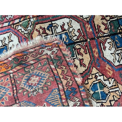 975 - A vintage early 20th Century Afghan Bukara Persian Islamic carpet floor rug. Having repeating medall... 