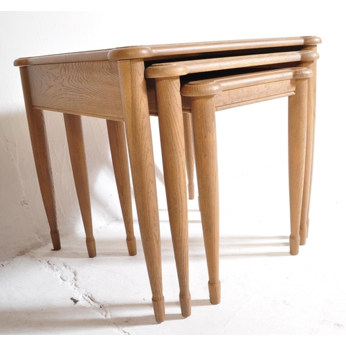 1044 - A retro 20th century oak wood nest of graduating tables. The tables being raised on turned and taper... 
