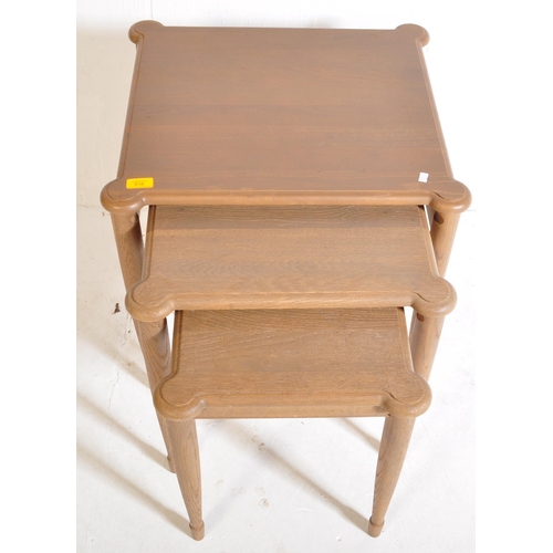 1044 - A retro 20th century oak wood nest of graduating tables. The tables being raised on turned and taper... 