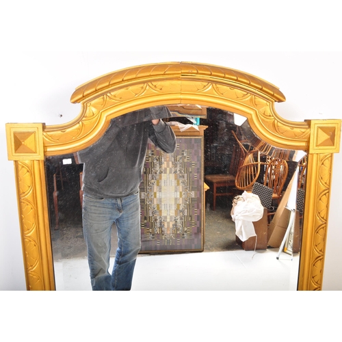 1051 - A large early 20th Century circa 1920s wooden gilt frame bevelled edge over mantel mirror. Having an... 