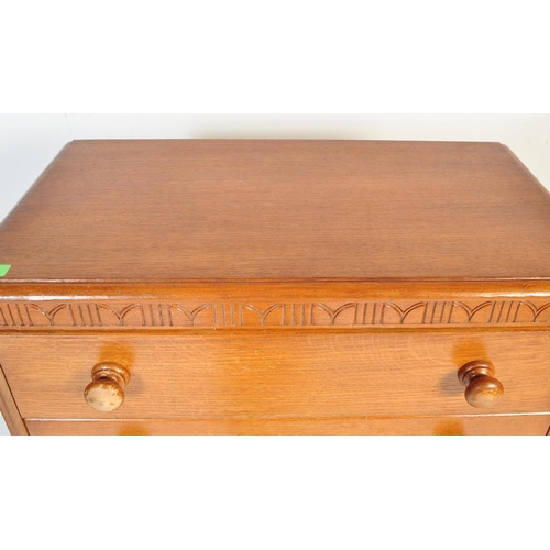 599 - A vintage 20th century circa 1940s light oak chest of drawers having a carved floral frieze over a b... 