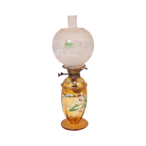 927 - An early 20th century glass oil lamp having a enamelled decorated reservoir in yellow colourway, wit... 