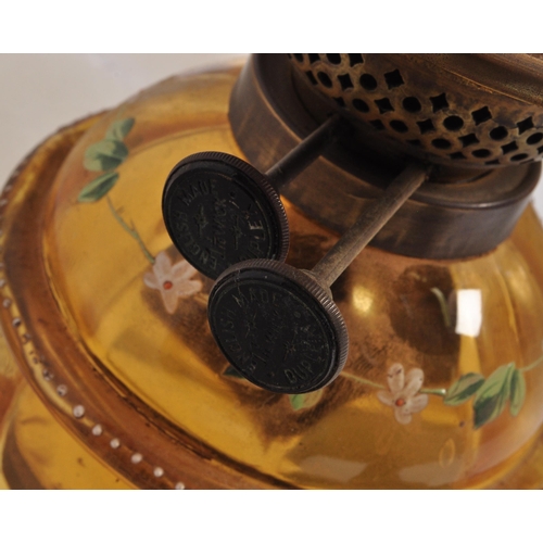 927 - An early 20th century glass oil lamp having a enamelled decorated reservoir in yellow colourway, wit... 