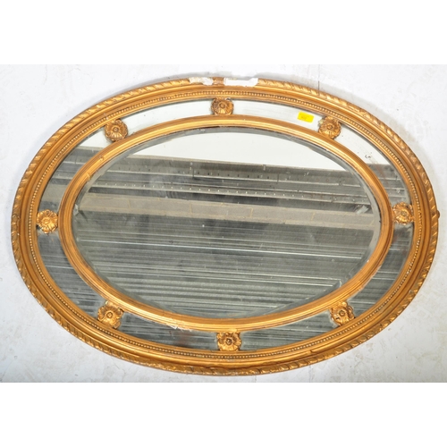 941 - An early 19th Century Regency gilt gesso plaster overmantel wall mirror of oval form. The central mi... 