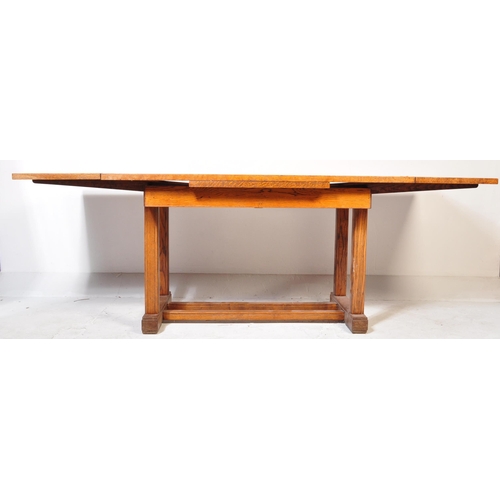 952 - A 1920’s oak Arts & Crafts large draw leaf refectory dining table raised on thick turned supports wi... 