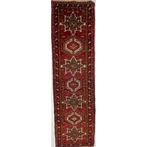 980 - A 20th century North West Persian Islamic Heriz floor rug carpet runner having a series of repeating... 