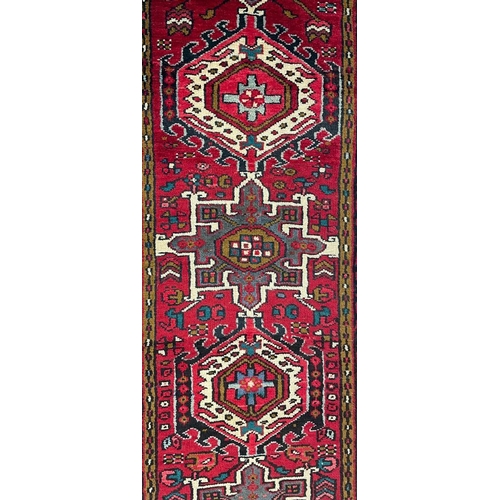 980 - A 20th century North West Persian Islamic Heriz floor rug carpet runner having a series of repeating... 