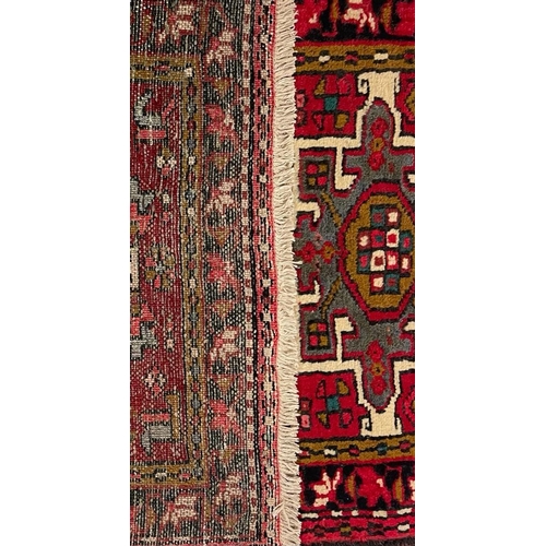 980 - A 20th century North West Persian Islamic Heriz floor rug carpet runner having a series of repeating... 