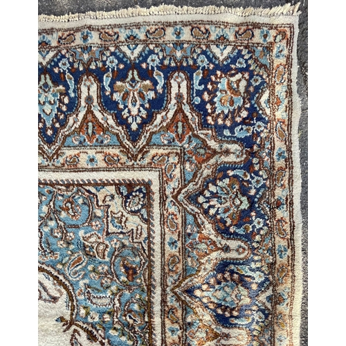 957 - An 20th Century Kirman Persian Islamic floor carpet rug having a central panel in cream and light bl... 
