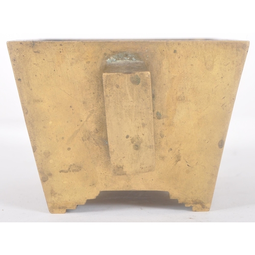 136 - An early 20th Century Chinese bronze censer ding bowl having engraved panels with twin archaic handl... 