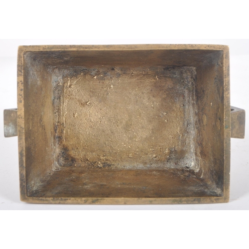 136 - An early 20th Century Chinese bronze censer ding bowl having engraved panels with twin archaic handl... 