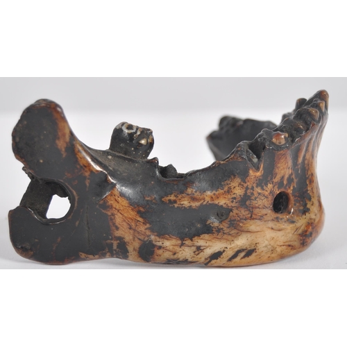 178 - A 19th century Nepalese witch doctors amulet. In the form of a human lower jaw, of charred and lacqu... 