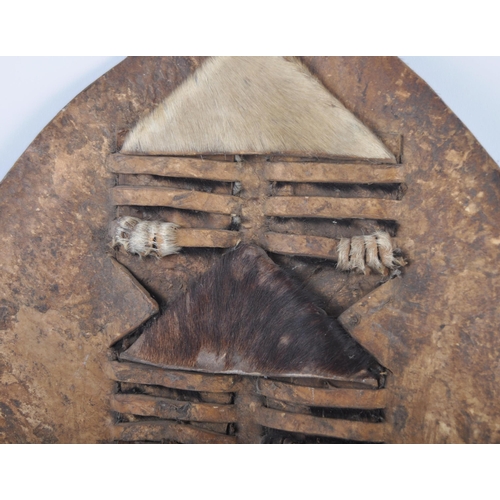 55 - A 19th Century African Tribal Zulu war shield. Hide construction and of typical form with pierced se... 