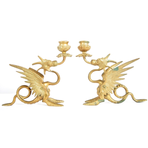 114 - A pair of 19th Century brass candlesticks in the form of mythical griffins. Both with candle sconce ... 