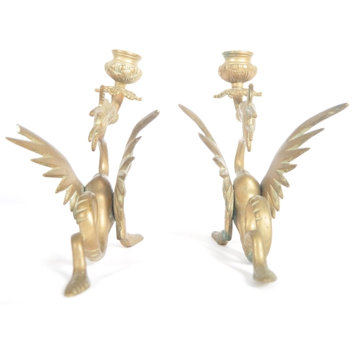 114 - A pair of 19th Century brass candlesticks in the form of mythical griffins. Both with candle sconce ... 