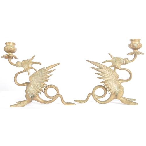 114 - A pair of 19th Century brass candlesticks in the form of mythical griffins. Both with candle sconce ... 