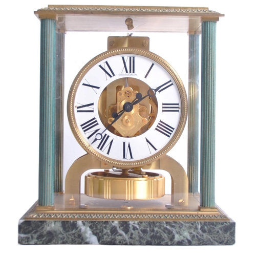 150 - A Jaeger LeCoultre Atmos clock, the glass and brass case with green enamel highlights and corner col... 