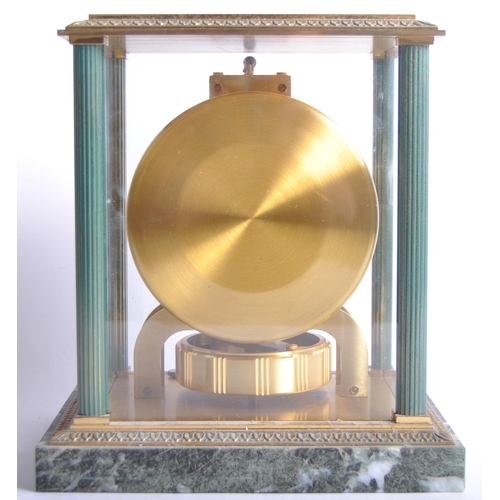 150 - A Jaeger LeCoultre Atmos clock, the glass and brass case with green enamel highlights and corner col... 