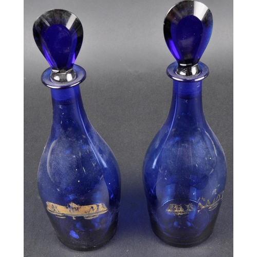 173 - A pair of early 19th Century Bristol Blue glass Indian Club shaped decanters. Gilded labels for Bran... 