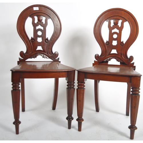 221 - A matching pair of 19th Century Victorian mahogany hall chairs having shaped armorial backrest with ... 