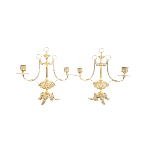 223 - A pair of 19th Century brass twin sconce candelabra having candlestick sconce raised on scrolled arm... 