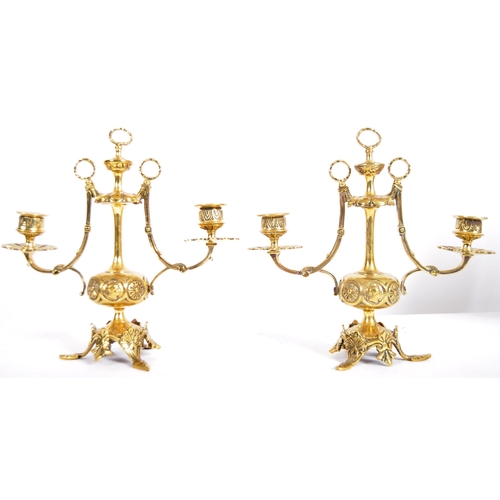 223 - A pair of 19th Century brass twin sconce candelabra having candlestick sconce raised on scrolled arm... 