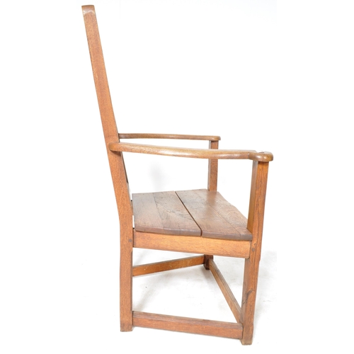 229 - A 19th Century Arts & Crafts solid oak armchair / throne chair having a panelled backrest with shape... 