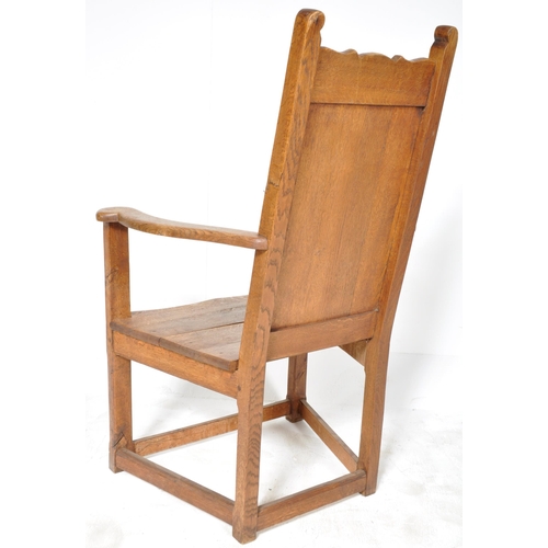 229 - A 19th Century Arts & Crafts solid oak armchair / throne chair having a panelled backrest with shape... 