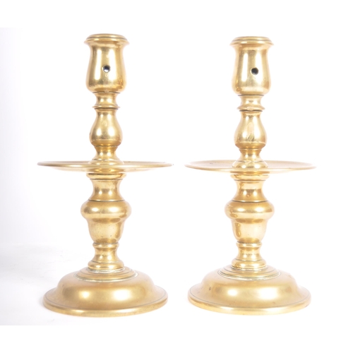 251 - A pair of 18th Century Dutch brass candlesticks having turned brass columns over large drip trays ra... 