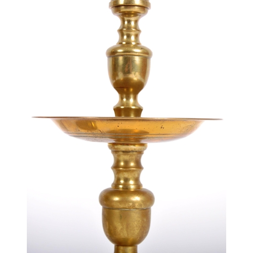 255 - A pair of 18th Century Dutch brass candlesticks having turned brass columns over large drip trays ra... 