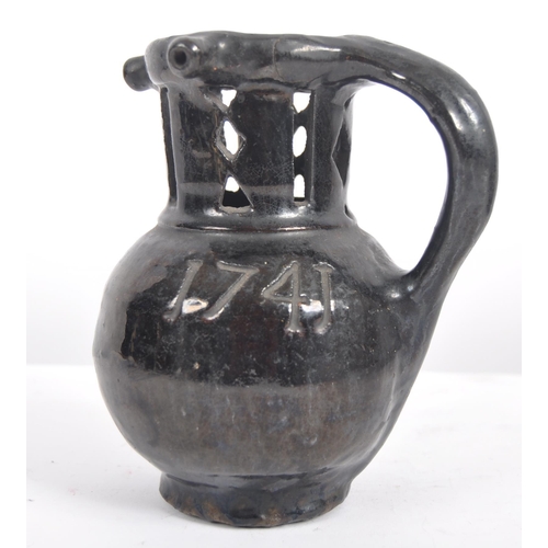 27 - An 18th Century Georgian pottery puzzle jug. Black painted finish with incised 1741 to globular body... 