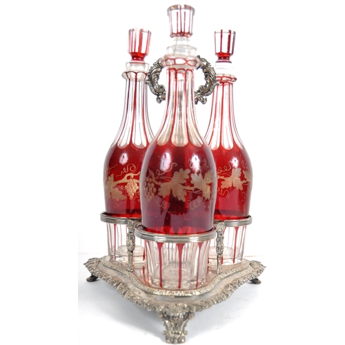 381 - A 19th Century Victorian cranberry glass triple decanter tantalus stand comprising of three etched g... 