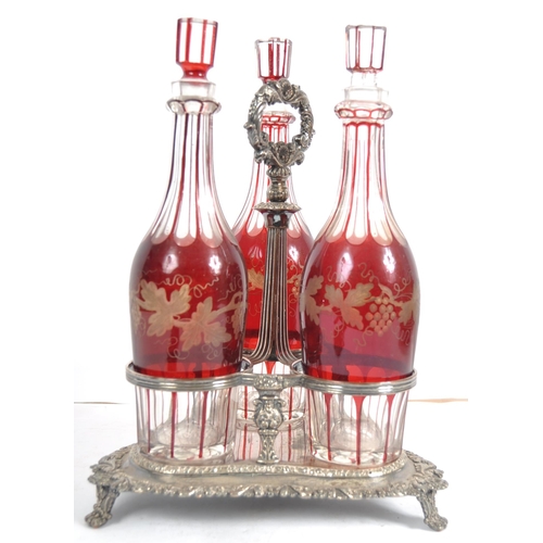 381 - A 19th Century Victorian cranberry glass triple decanter tantalus stand comprising of three etched g... 