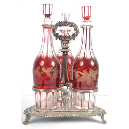 381 - A 19th Century Victorian cranberry glass triple decanter tantalus stand comprising of three etched g... 