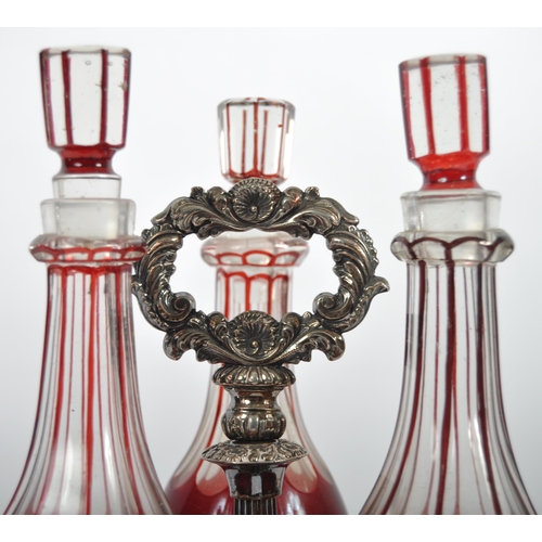 381 - A 19th Century Victorian cranberry glass triple decanter tantalus stand comprising of three etched g... 