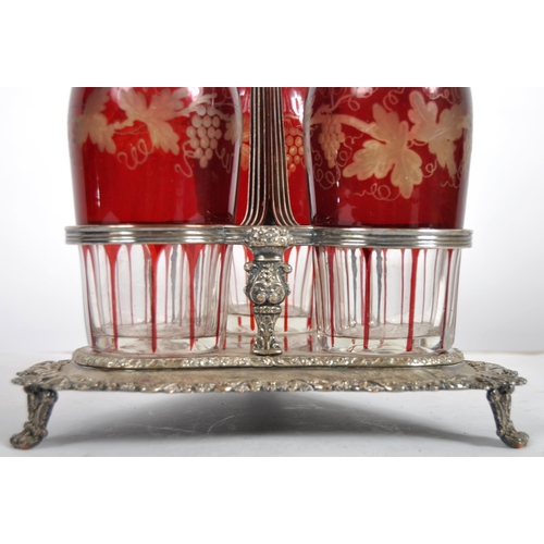 381 - A 19th Century Victorian cranberry glass triple decanter tantalus stand comprising of three etched g... 