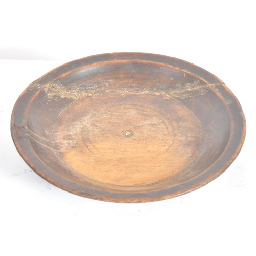 418 - A 17th century English church collection treen plate. A carved raised edge rim plate supported on ra... 