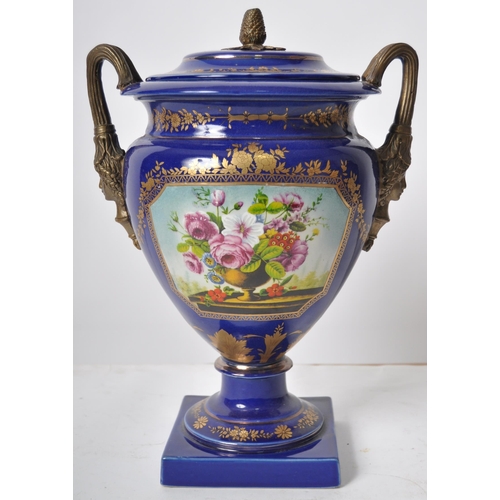 445 - An early 20th Century continental porcelain lidded urn in the Dresden style, having a deep cobalt gr... 