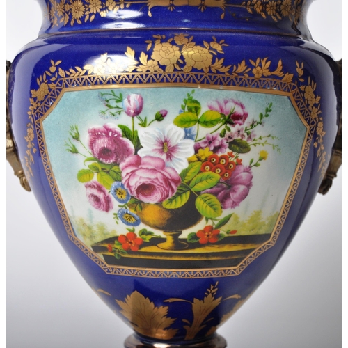 445 - An early 20th Century continental porcelain lidded urn in the Dresden style, having a deep cobalt gr... 