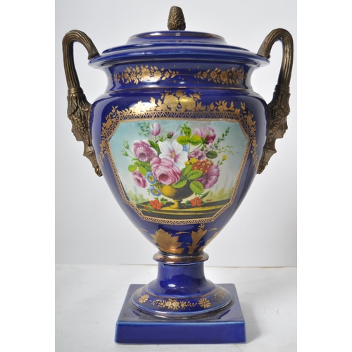 445 - An early 20th Century continental porcelain lidded urn in the Dresden style, having a deep cobalt gr... 