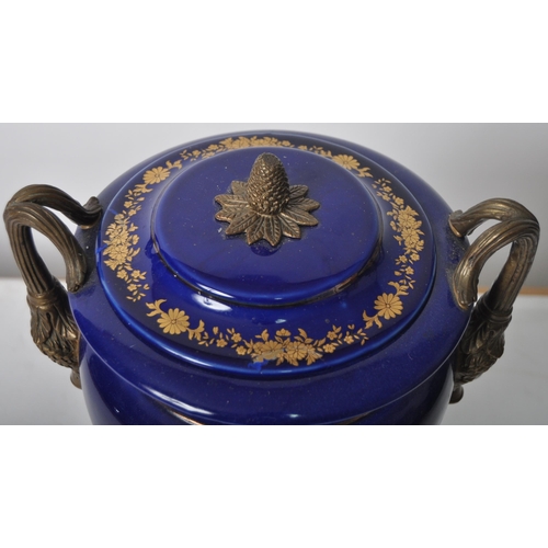 445 - An early 20th Century continental porcelain lidded urn in the Dresden style, having a deep cobalt gr... 