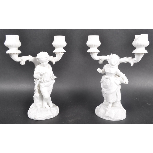 519 - A pair of early 20th Century Parian ware blanc de chine porcelain figural candlesticks in the manner... 