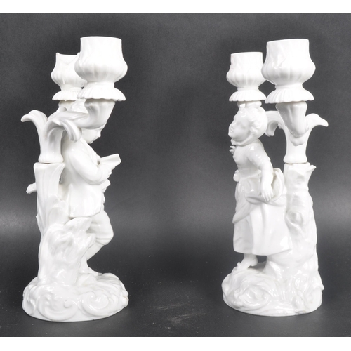 519 - A pair of early 20th Century Parian ware blanc de chine porcelain figural candlesticks in the manner... 