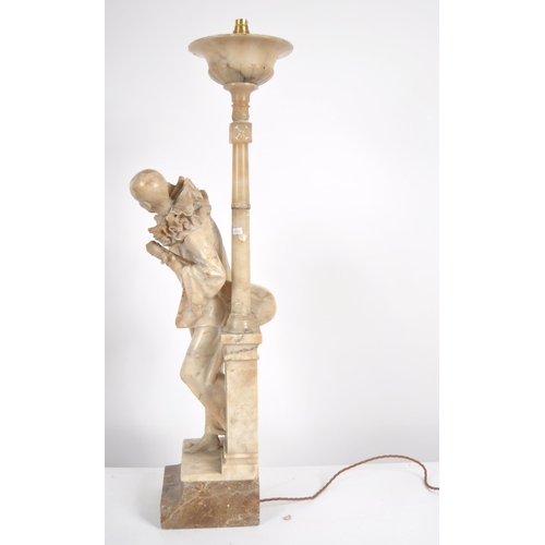 548 - A 20th century marble torchere statue. Depicting a standing Pierrot with a gittern under his arm lea... 