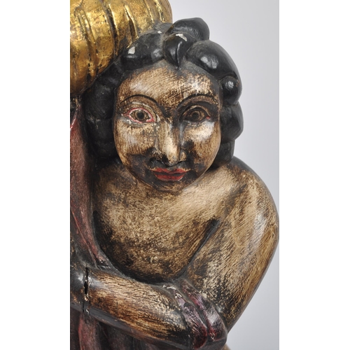 558 - A 20th Century hand carved and painted wooden statue of a cherub holding a torch. Measures approx; 7... 